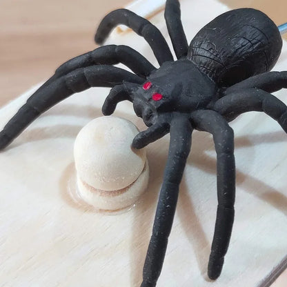 Close-up of a realistic black spider on a wooden prank box lid, highlighting its detailed design and red eyes. Fun gift for prank enthusiasts.