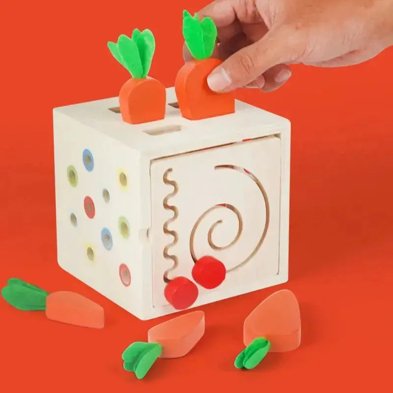 Carrot shapes being placed in wooden shape sorter cube.